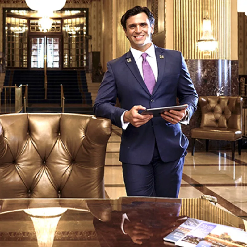 A Les Clefs d'Or concierge in a suit standing in an elegant hotel lobby