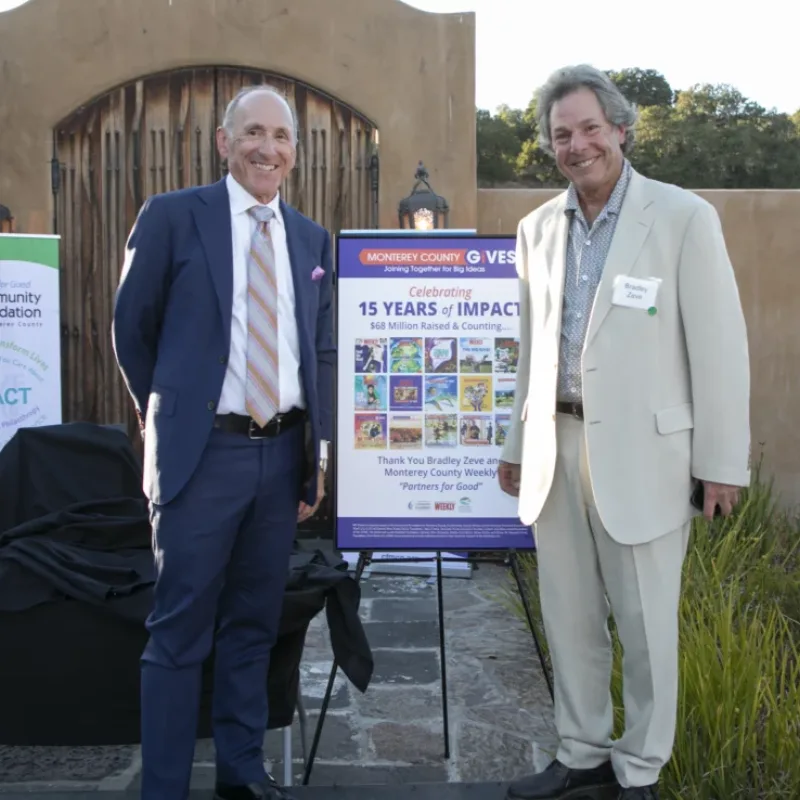 Two Monterey County Gives! campaign leaders beside a 15 Years of Impact sign