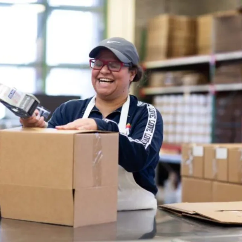 A Women's Bean Project team member laughing while packing product boxes